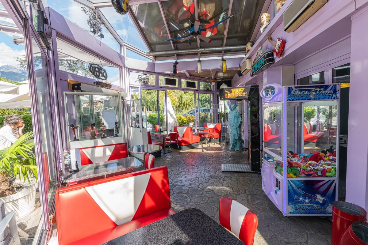 Intérieur du American Pub à Sion avec banquettes rouges rétro, bornes de jeux et ambiance américaine idéale pour déguster burgers et cocktails