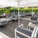 Terrasse lounge du American Pub à Sion avec fauteuils confortables et parasols, idéale pour déguster burgers, bières et cocktails