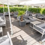 Terrasse extérieure du American Pub à Sion avec salons lounge et parasols, idéale pour savourer burgers, cocktails et bières