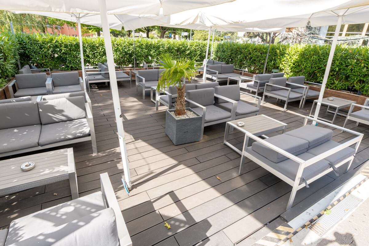 Terrasse extérieure du American Pub à Sion avec salons lounge et parasols, idéale pour savourer burgers, cocktails et bières